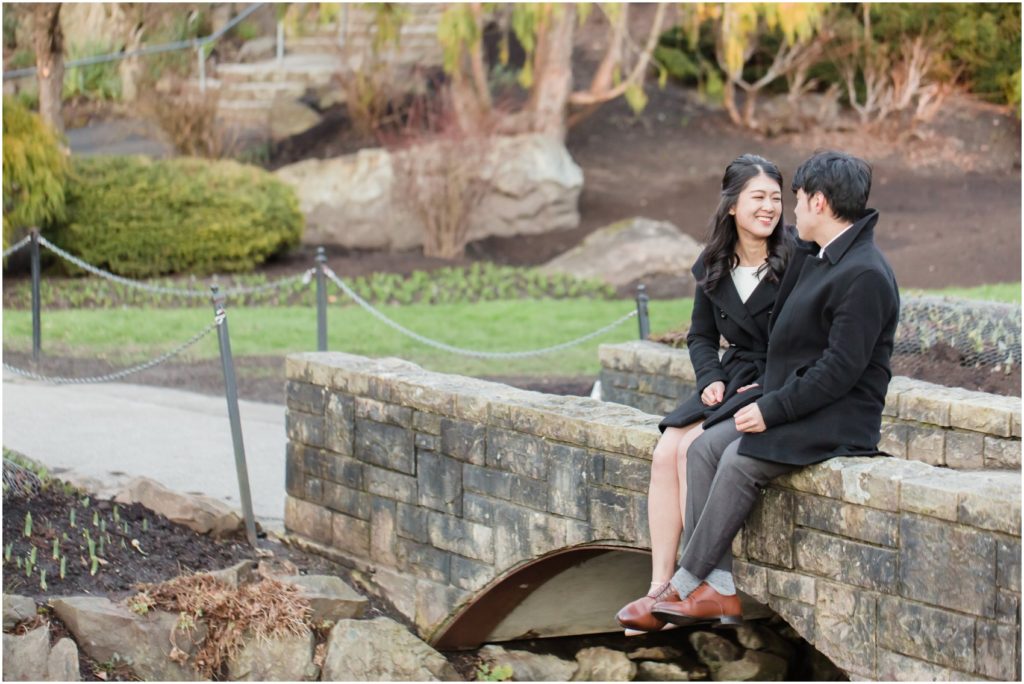 Queen Elizabeth Park engagement photos, bride and groom sitting on a bridge