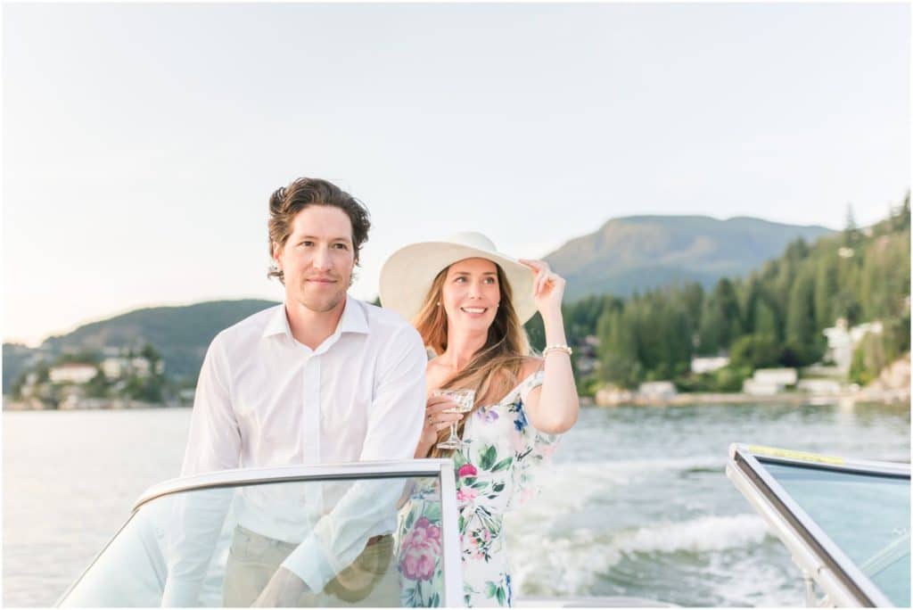 Vancouver Engagement Photo in West Vancouver's very own Lake Como, couple on a boat heading out, groom is driving the boat, bride is holding on to a glass of champagne and holding onto hat