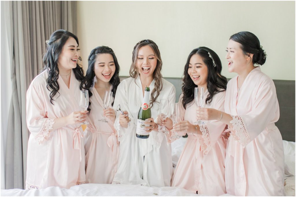 Bride popping champagne with bridesmaids in hotel in Burnaby, Vancouver