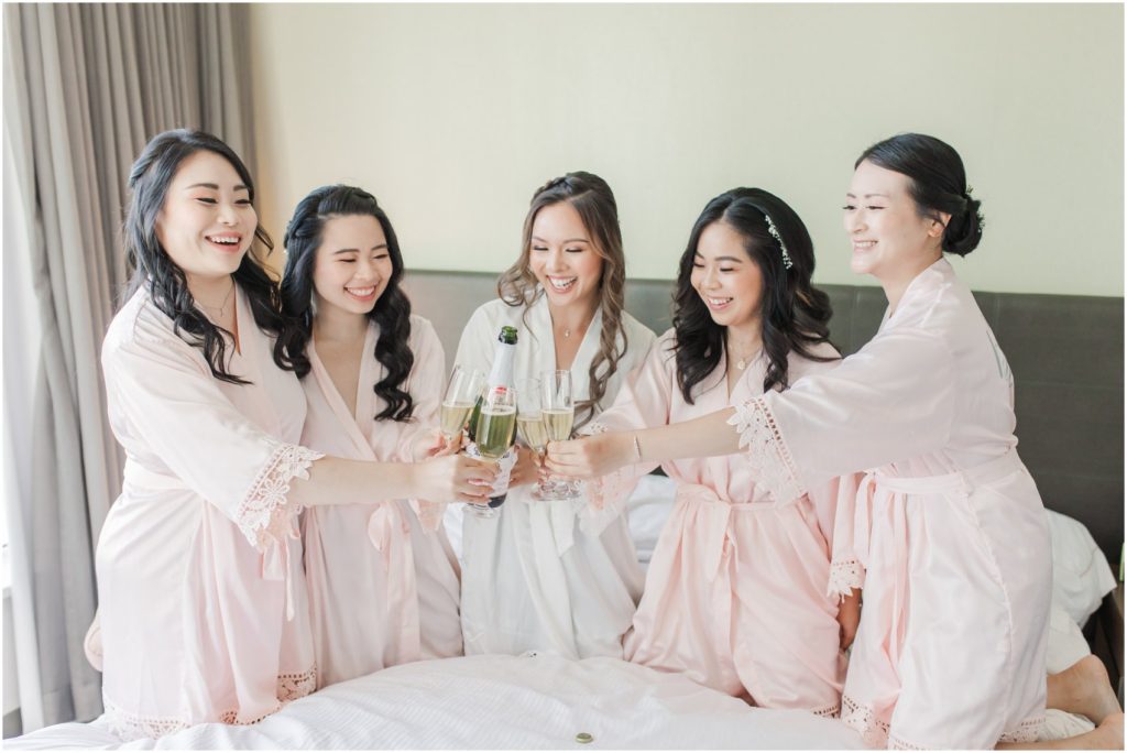 Bride popping champagne with bridesmaids in hotel in Burnaby, Vancouver